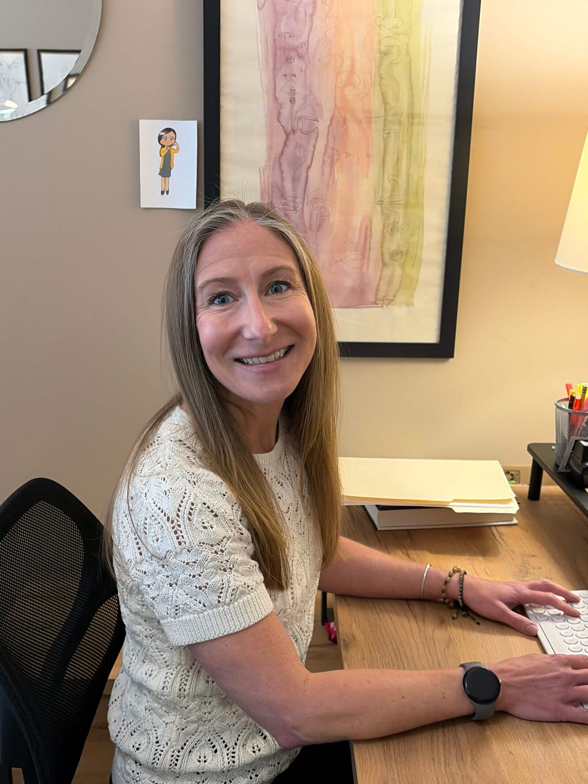Smiling woman typing at wooden desk.
